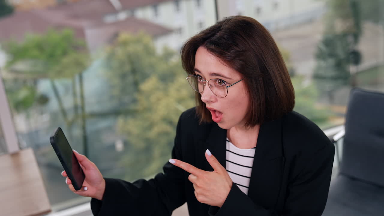 Surprised young lady looking at her smartphone. Woman receiving shocking news or information. Top view.