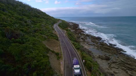 cement construction truck drives along great ocean road in victoria, australia - aerial view