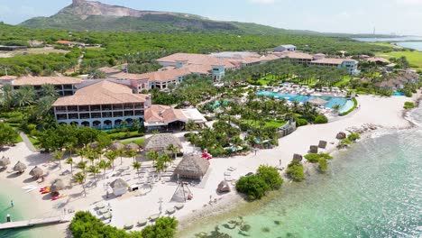 high angle aerial orbit around white sand beautiful caribbean resort and crystal clear water, santa barbara beach curacao