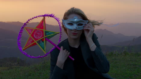 slow motion shot of a woman wearing a mask and holding a star lantern at sunset