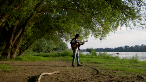 a musician plays guitar by the river