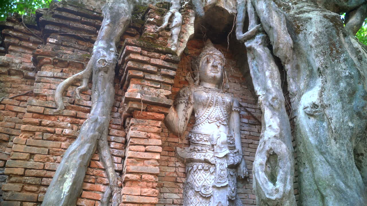 Ancient Buddha head entangled in tree roots at Ayutthaya ruins site, relic of archaeology