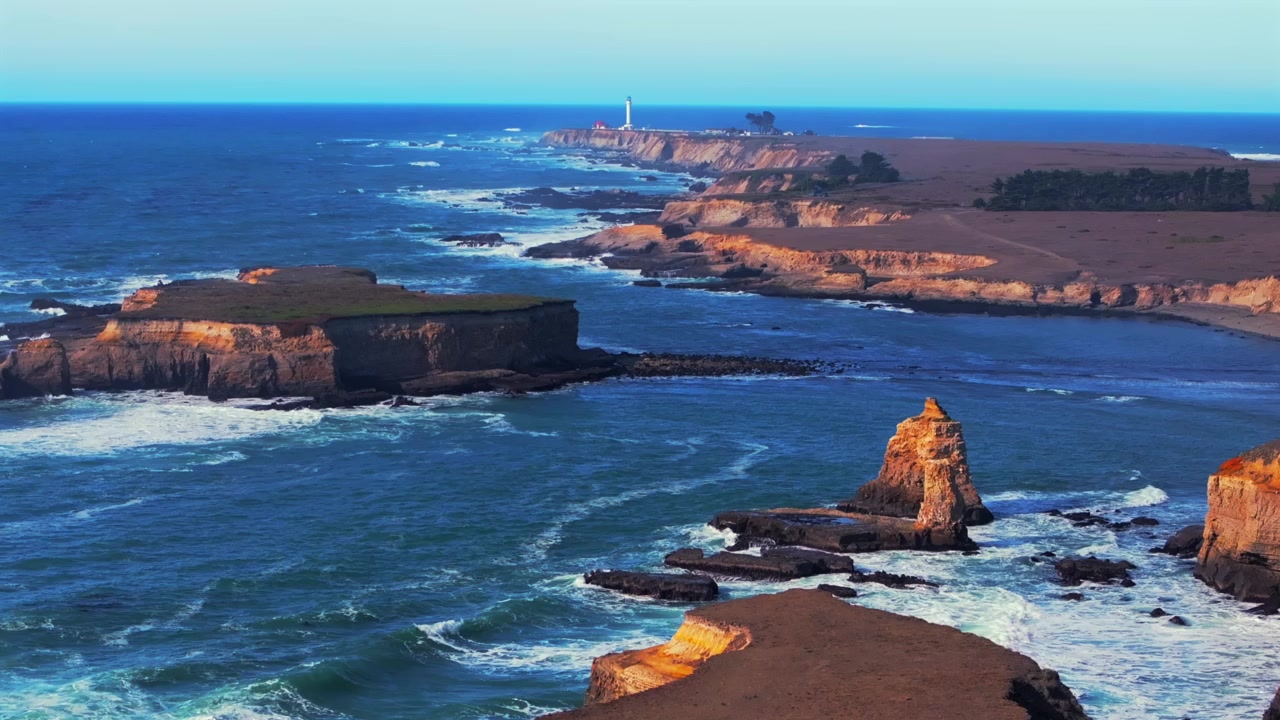 Vista aérea de drone diurna e ensolarada da costa de Mendocino, incluindo ilhas, o Farol de Point Arena Rock e a costa acidentada da Califórnia, com ondulação e formações rochosas. Fort Bragg, San Francisco, Oceano Pacífico Norte. Voo costeiro ascendente.