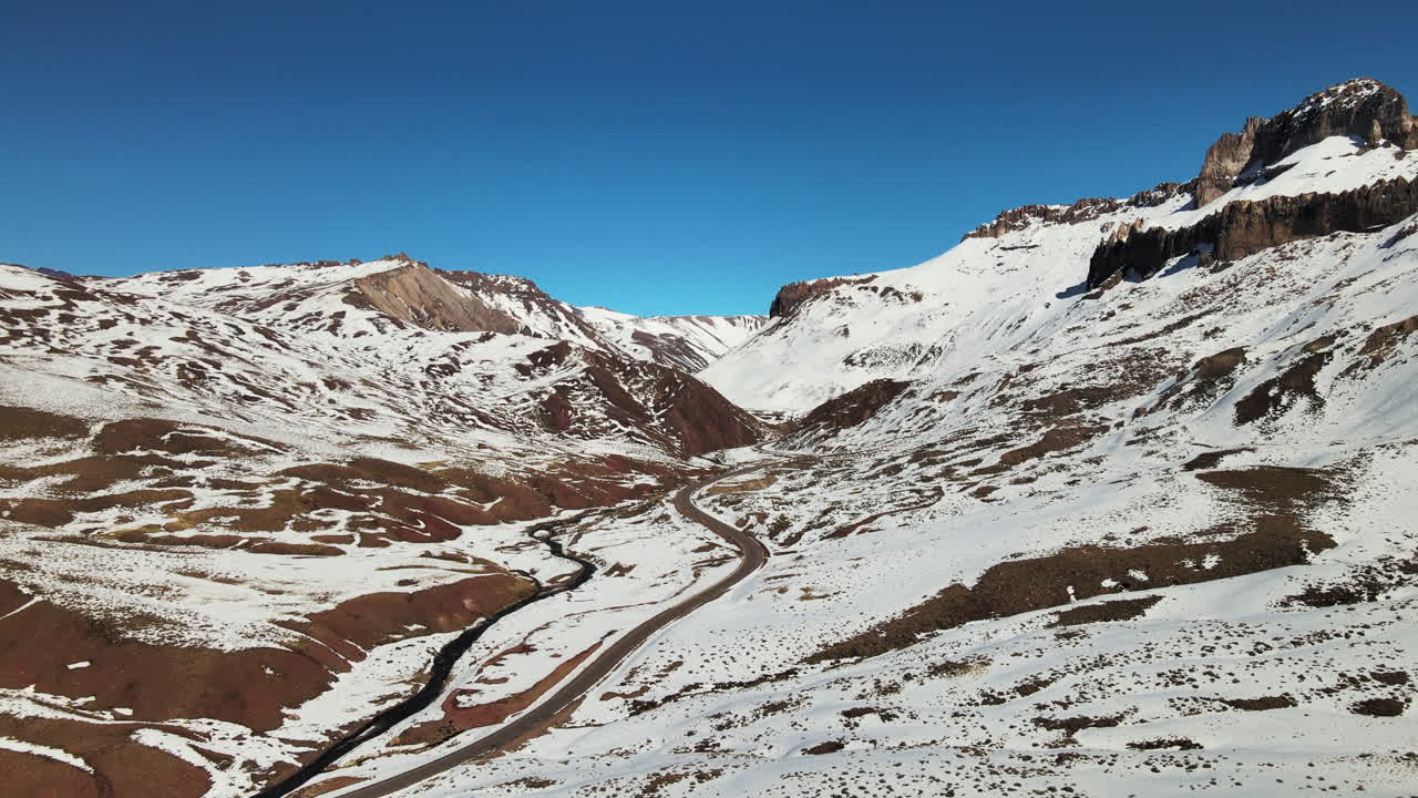 Magnifica immagine da drone del percorso che porta alla valle innevata di Las Leñas, che cattura la bellezza mozzafiato del viaggio tra i paesaggi andini.