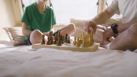 father and son playing chess sitting on the campervan bed