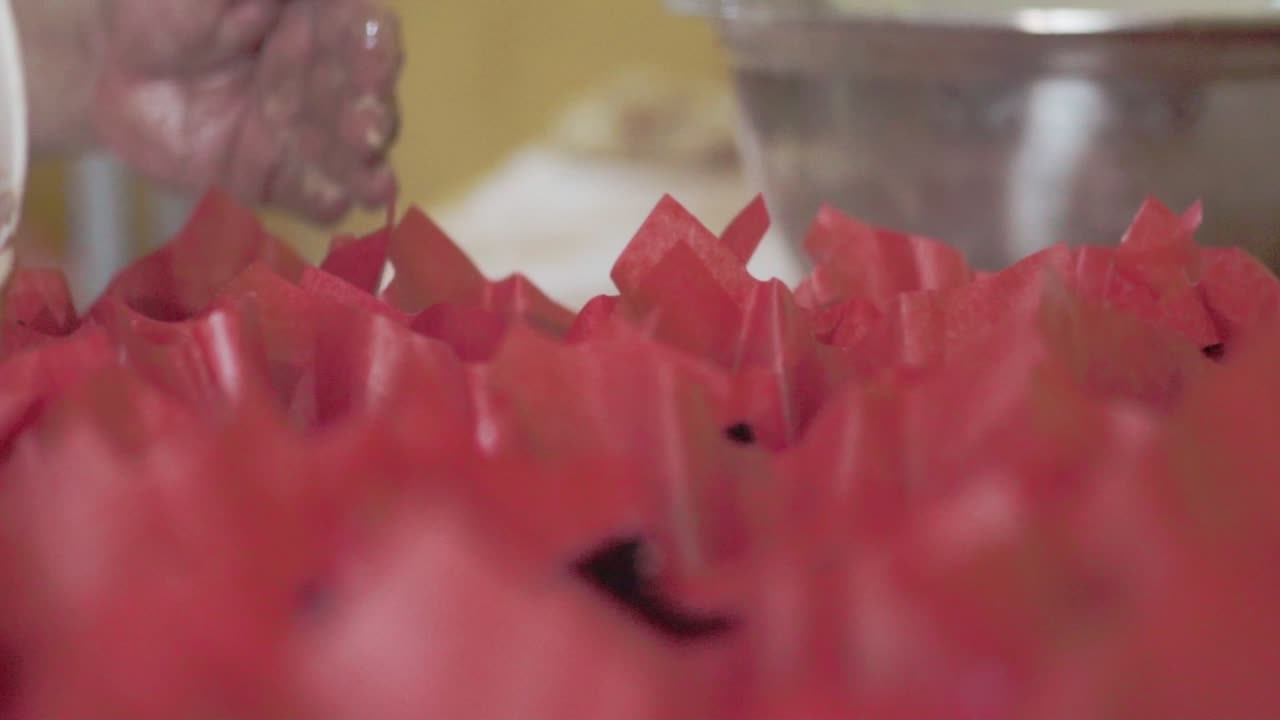 베이킹 을 위해 컵케이크 라인 에 반죽 을 부는 페이스트리 셰프 의 클로즈업