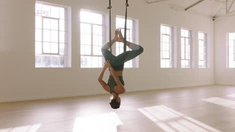 mujer de yoga aéreo practicando la postura de mariposa invertida colgando boca abajo usando una hamaca disfrutando de un estilo de vida de acondicionamiento físico saludable haciendo ejercicio en el estudio entrenando meditación al amanecer