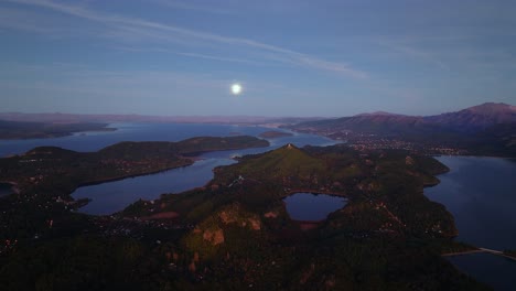 Aerial-View-of-Lake-Nahuel-Huapi-Near-Bariloche,-Rio-Negro,-Argentina-In-The-Evening-With-The-Full-Moon-On-The-Horizon