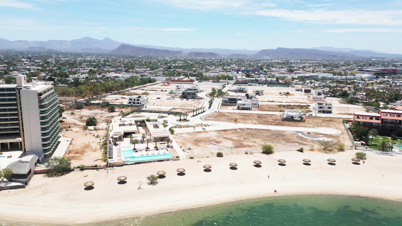 Beachfront view of La Paz’s Playa Posada with resorts and distant city landscape