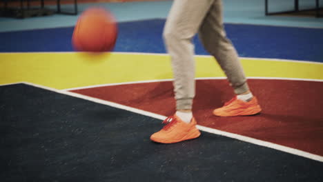 close up of a female basketball player bouncing the ball on outdoor court at night