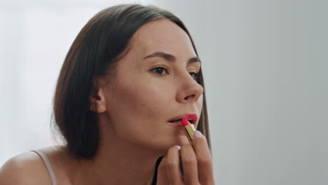 mujer enfocada labios maquillaje preparando en casa primer plano. cara de la chica aplicando lápiz labial