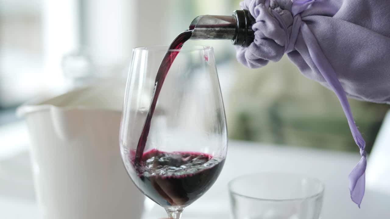 primer plano desconocido camarero mano vertiendo vino en vaso en el interior. mujer joven mano tomando vaso de vino con bebida en el interior del restaurante.