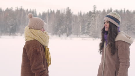 front view of mother and daughter in winter clothes approach and hugging in a snowy forest