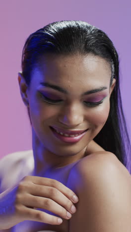 vertical video of biracial woman with black hair and make up smiling, copy space, slow motion