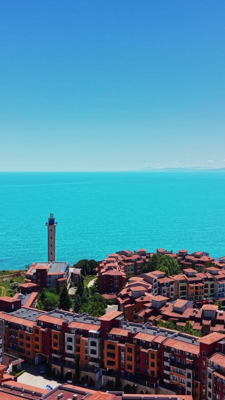 Vista di città costiera con faro e mare azzurro in una giornata di sole