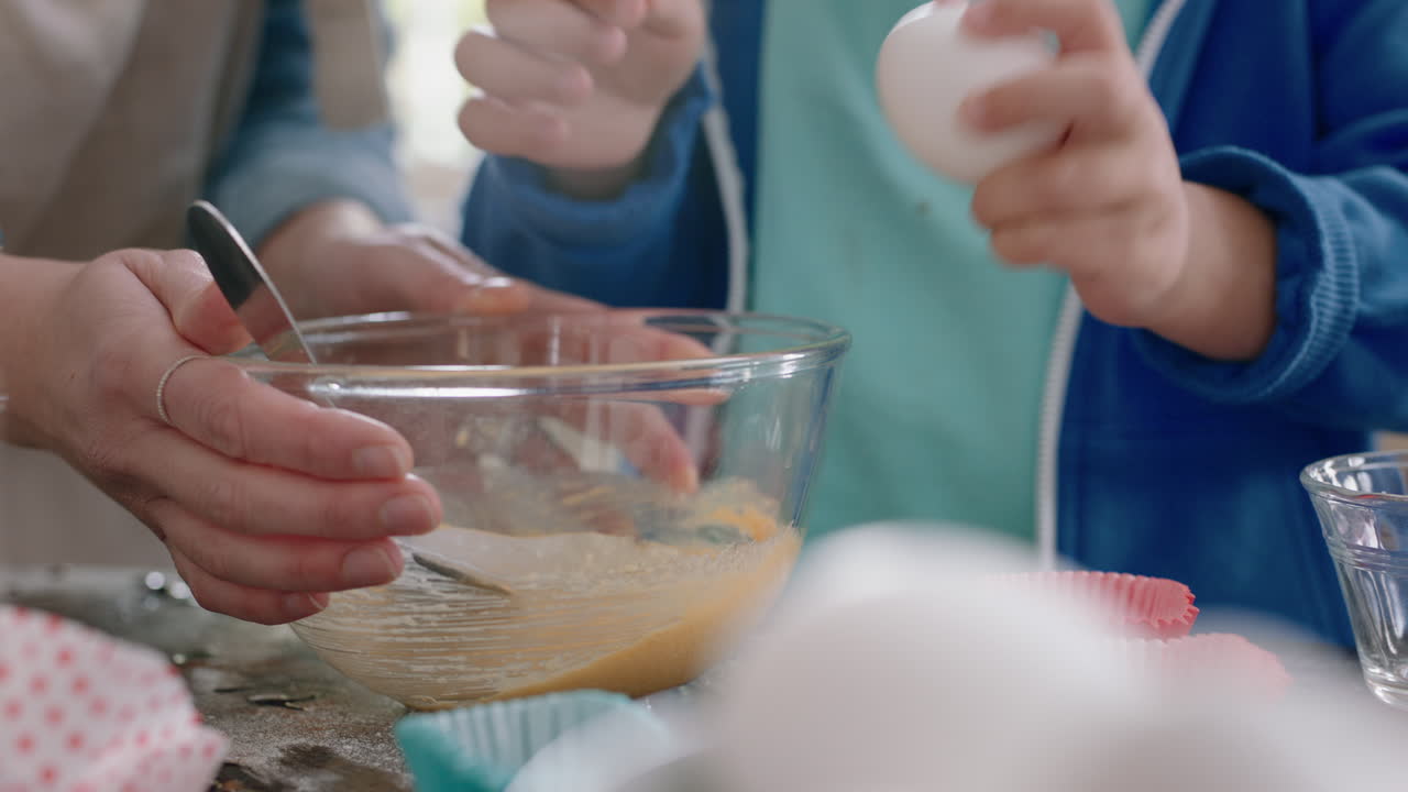 cute little boy helping mother bake in kitchen mixing ingredients breaking eggs into bowl preparing recipe at home with mom