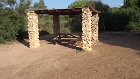 a nice picnic table under a stone and wood roof in a park