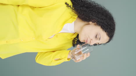 Vertical-video-of-The-young-woman-is-drinking-water.