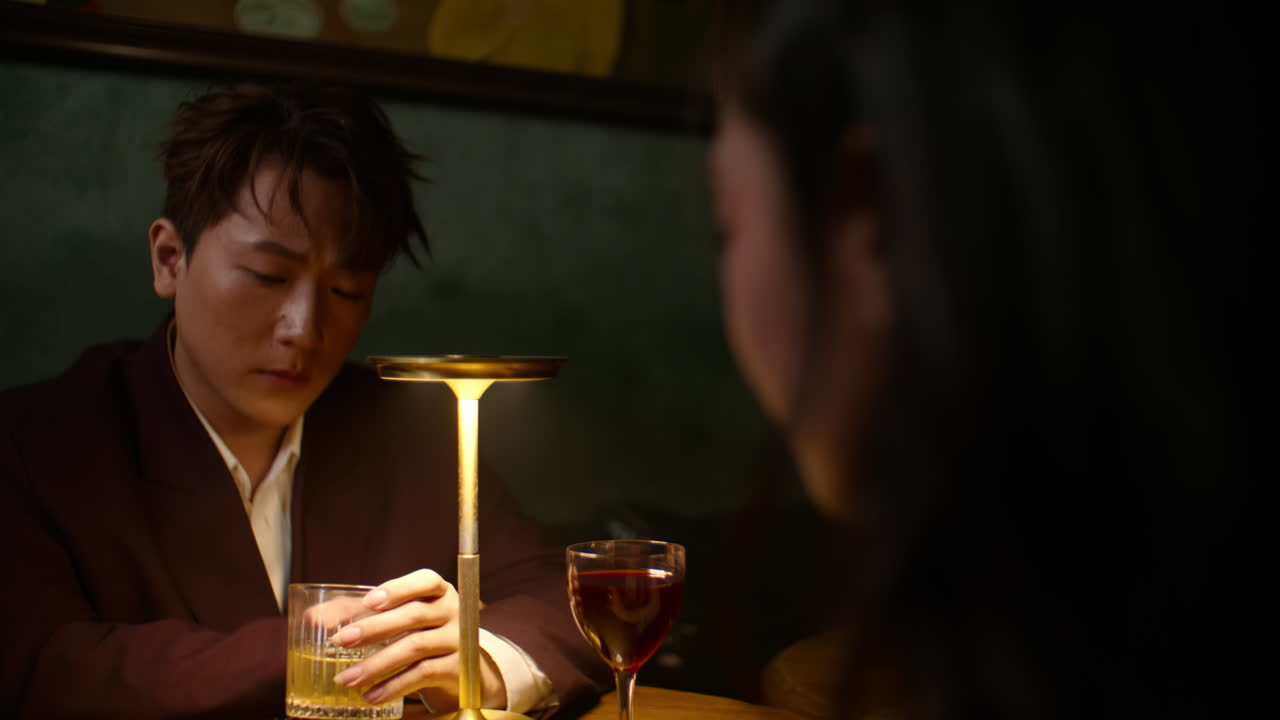 Sad Asian couple at bar, contemplating breakup under dim light, emotional mood