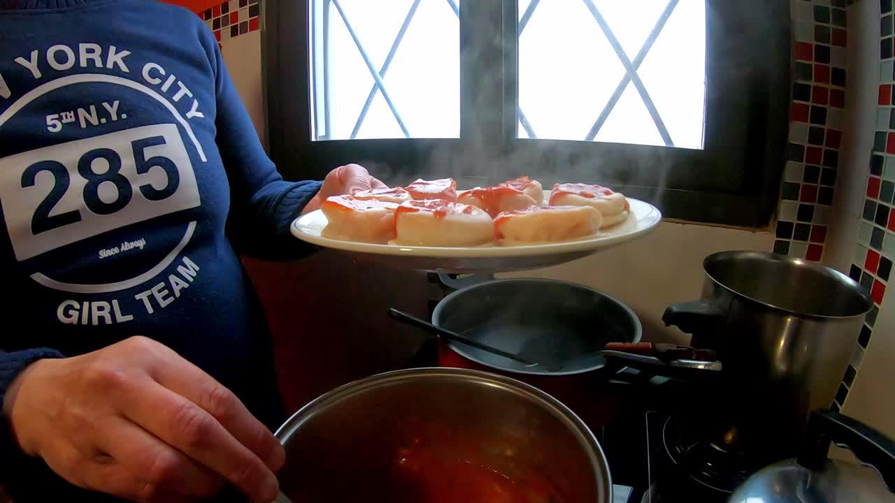 Woman putting tomato sauce with a spoon, Italian pasta in the kitchen