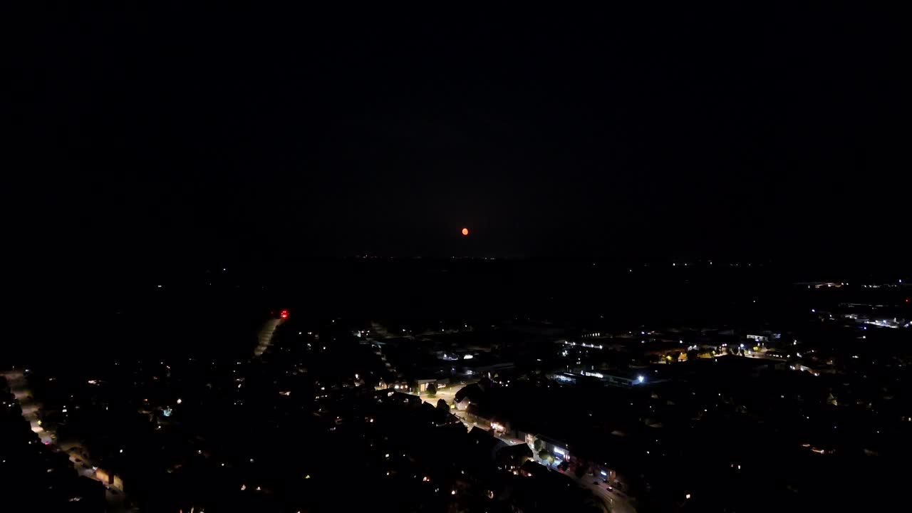 Night sky in suburbia or American metropolis town. Aerial wide shot. Cars on street in background. Lighting small city district neighborhood in USA at midnight. Peaceful housing area of America