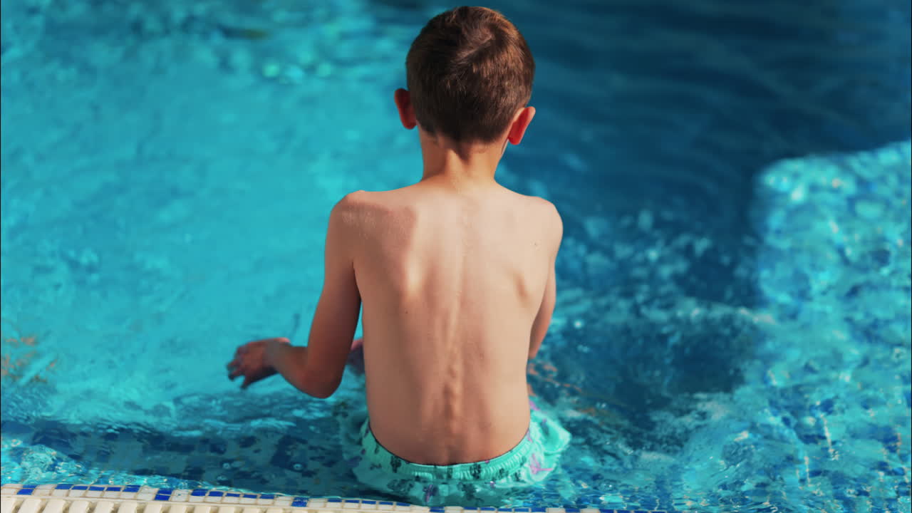 Overhead shot of a young boy playing in a bright blue swimming pool