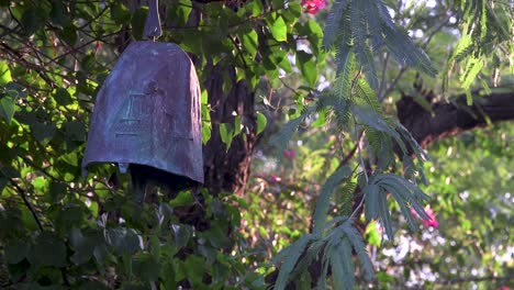 close-up of a metal garden bell hanging in a desert mesquite tree