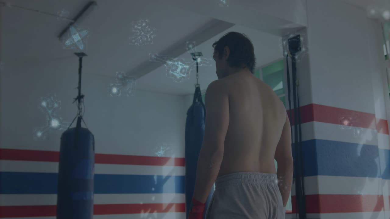 Boxer shifting weight and turning to camera in boxing gym, particles highlighting focus near bags