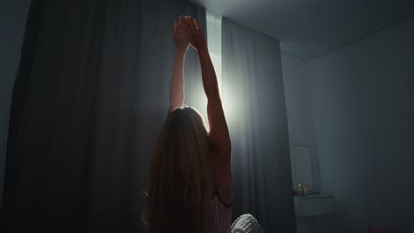 mujer estirándose en la cama al amanecer