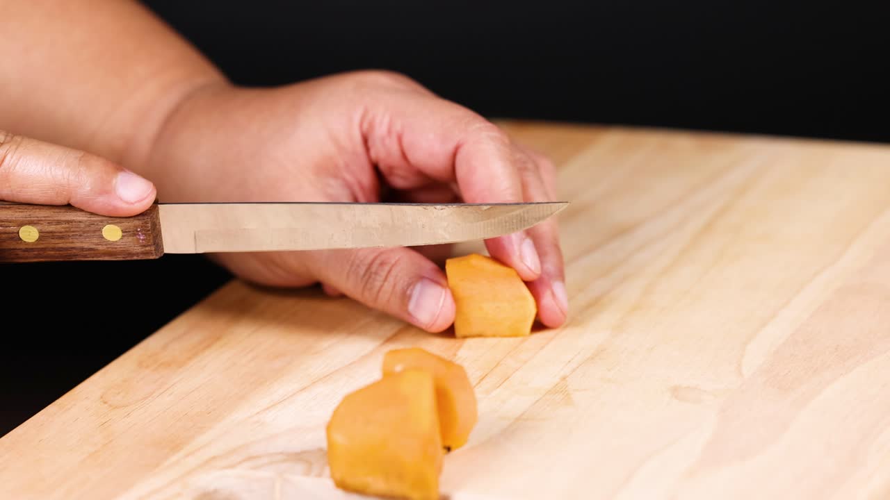 manos cortando cuidadosamente el caqui con un cuchillo