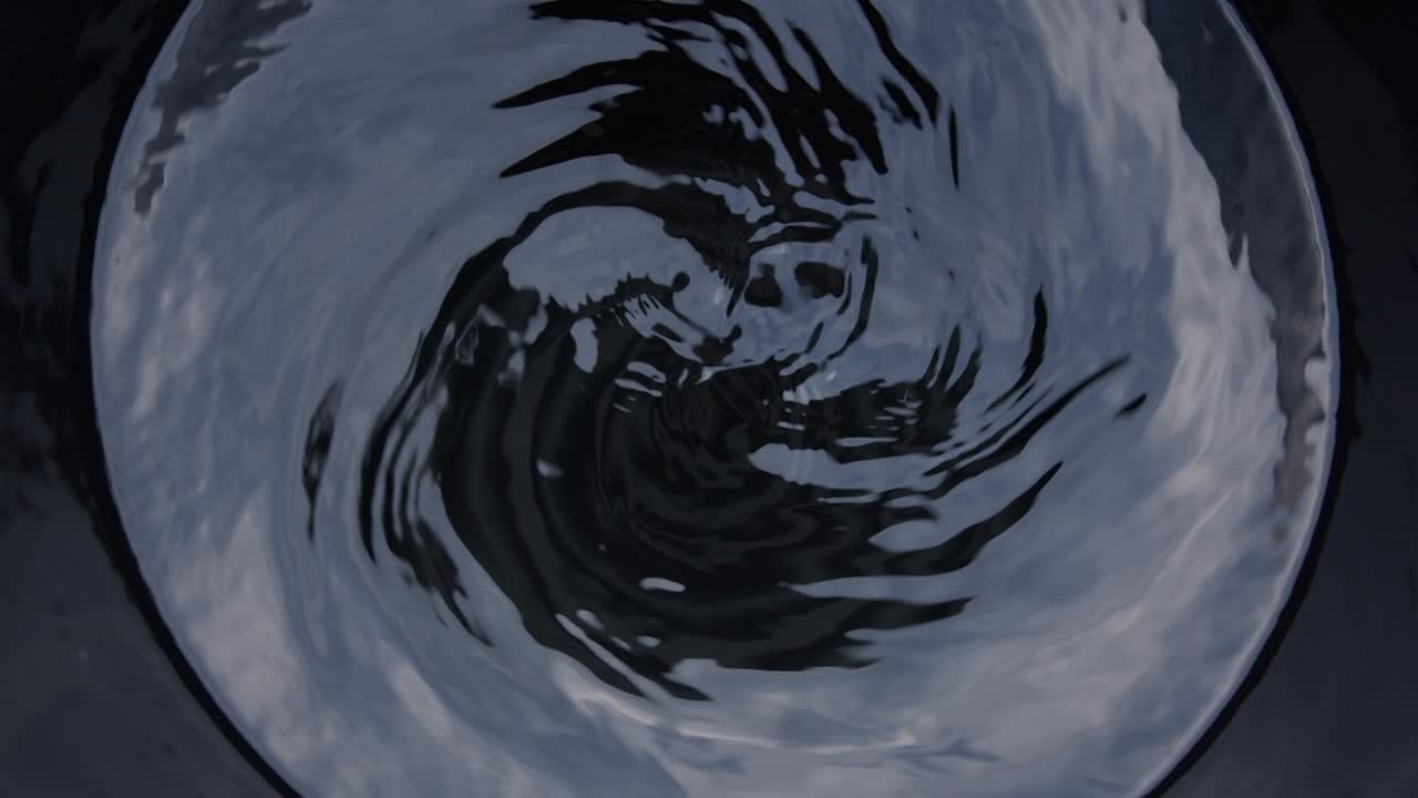 Blurred moving Water spins in the black barrel.