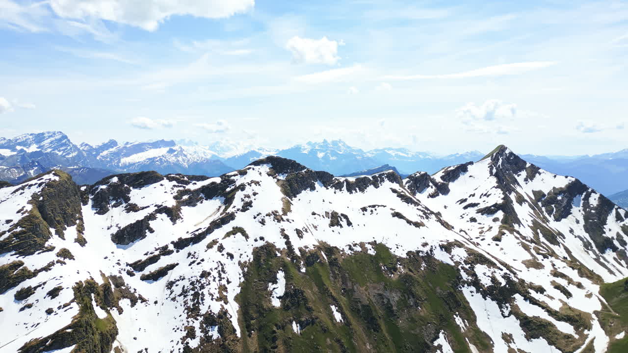 Aerial: snowy mountain peak and Dents du Midi mountain range in the back during the day above Lake Lioson, in the canton of Vaud, Switzerland, crane up drone shot