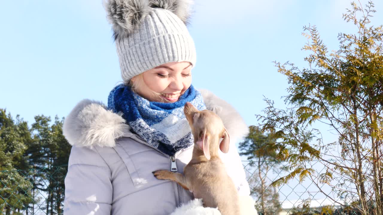 여자 는 겨울 밖 에서 작은 개 와 함께 놀고 있다