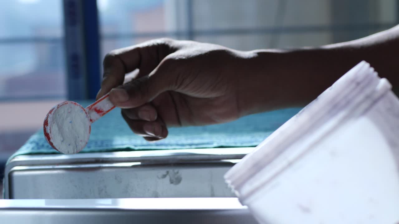 Pouring washing powder in plastic tray