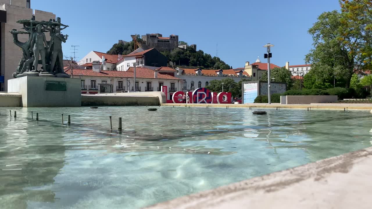 fuente de agua en leiria cerca de un castillo.