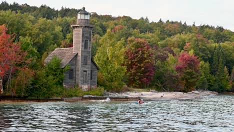 Kayaker-passing-east-channel-lighthouse,-Pictured-Rocks-National-Lakeshore,-Michigan