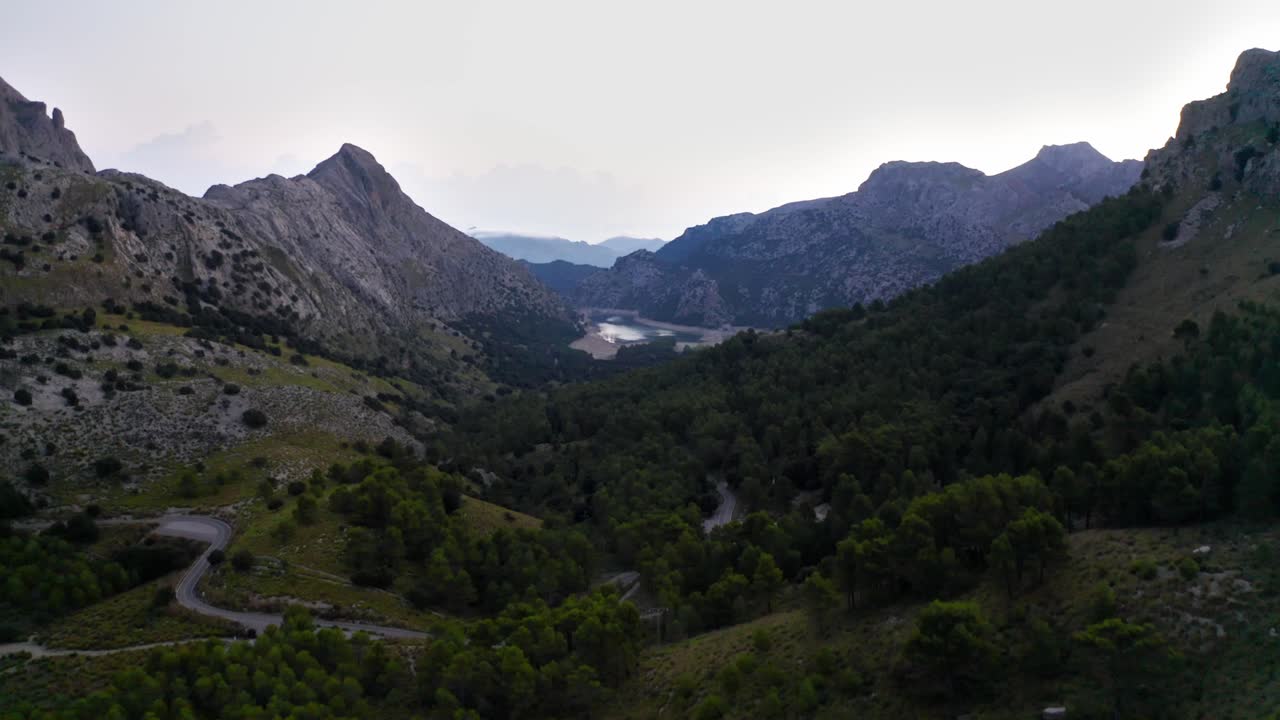 macizo montañoso en el valle con carreteras sinuosas y bosques, tiro aéreo de avión no tripulado