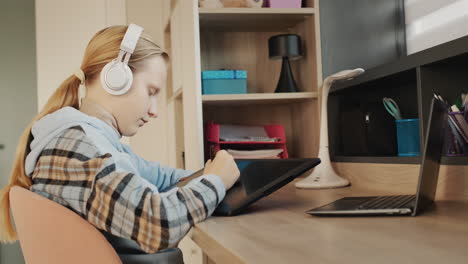 a girl in headphones draws on a graphics tablet in her room.