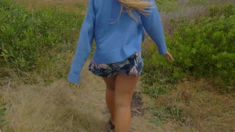 girl in blue sweater walking with hair blowing in the wind - track at crescent head lookout and big nobby in sydney, nsw, australia