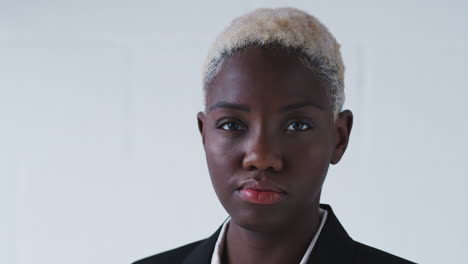 Portrait-Of-Determined-Young-Businesswoman-Wearing-Suit-Standing-Against-White-Studio-Wall