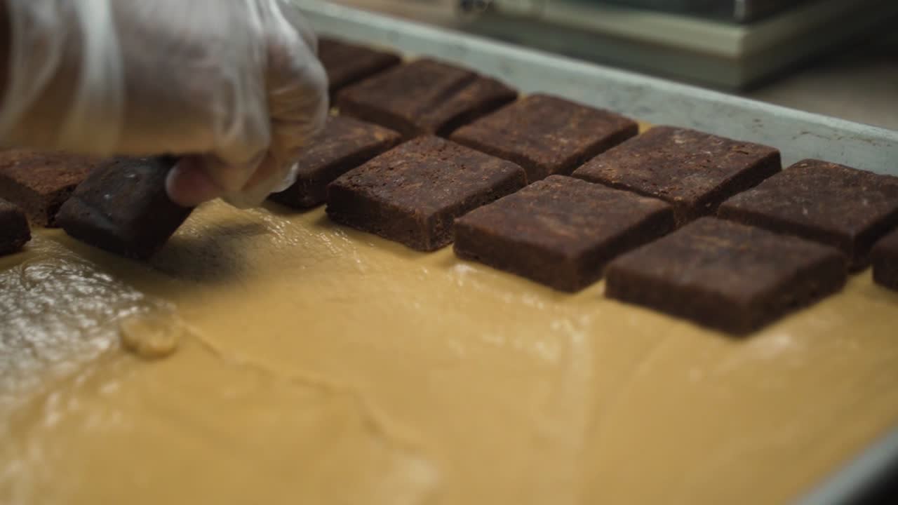 Placing brownies in a bed of peanut butter mix. This was taken at a higher frame rate and has been converted to a slow motion video clip.