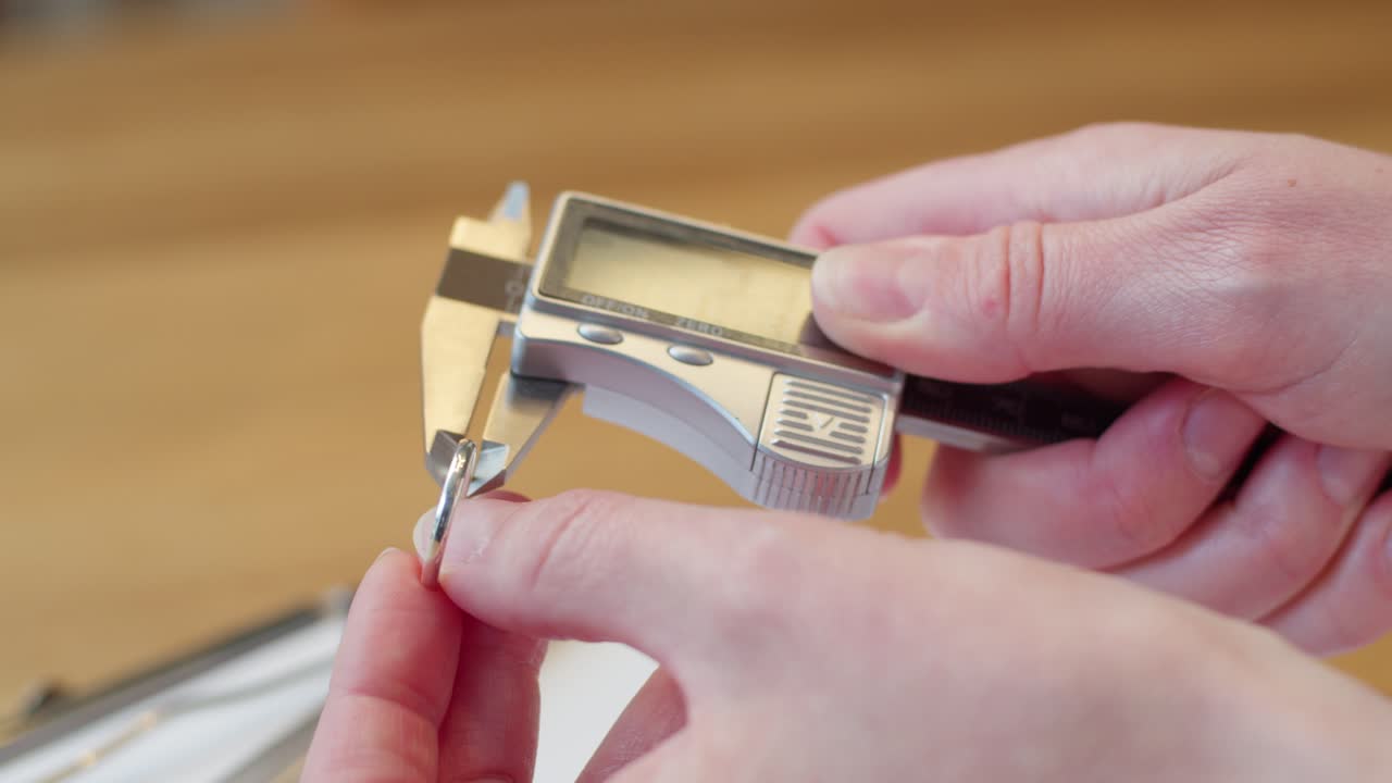 Wedding ring getting measured by woman's hand and writing on clipboard and paper with pen