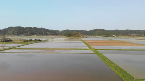 beautiful sideways flight over water filled rice fields in japanese countryside