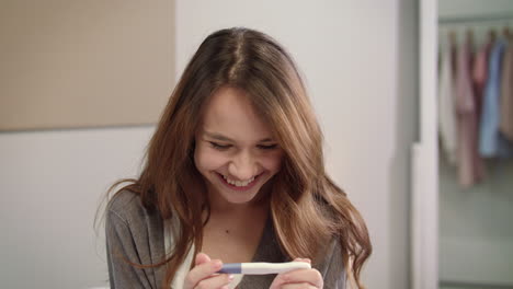 shocked woman looking positive pregnancy test result