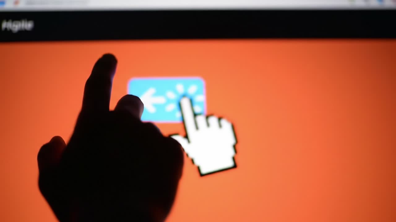 A close-up of a hand gently touching a vibrant screen displaying a pink arrow on a bright orange background, showcasing user interaction with technology.