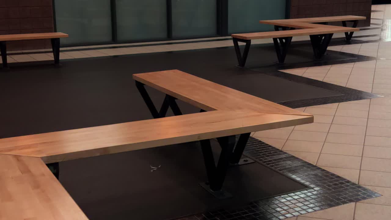 Slow motion walking pan through modern indoor space with wooden benches and clean geometric flooring