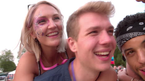 Young-friends-piggy-backing-at-a-music-festival,-close-up