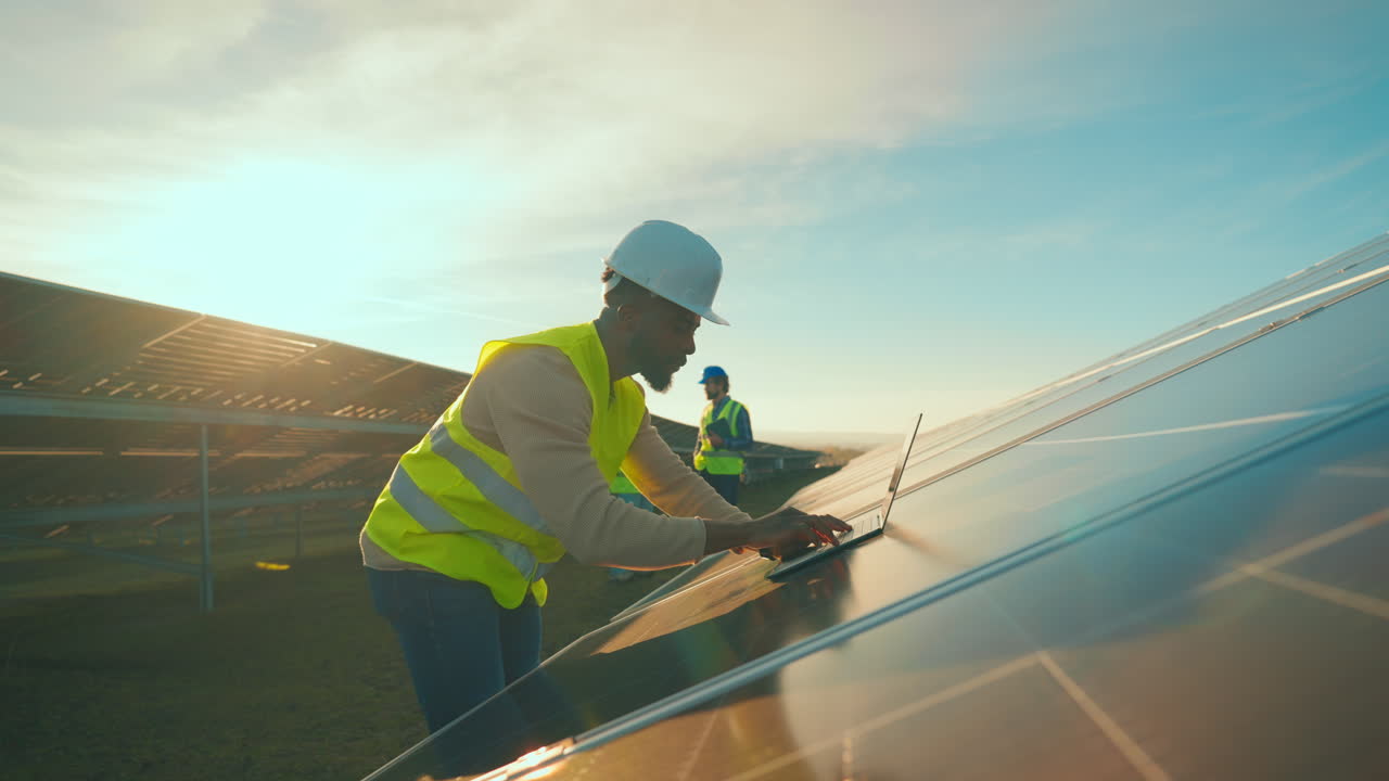 Workers inspecting solar panels with laptops