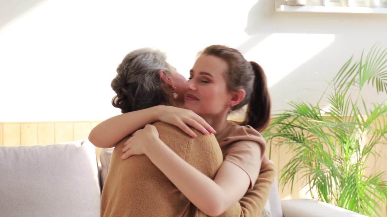 Giovane donna che abbraccia una donna anziana su un divano a casa