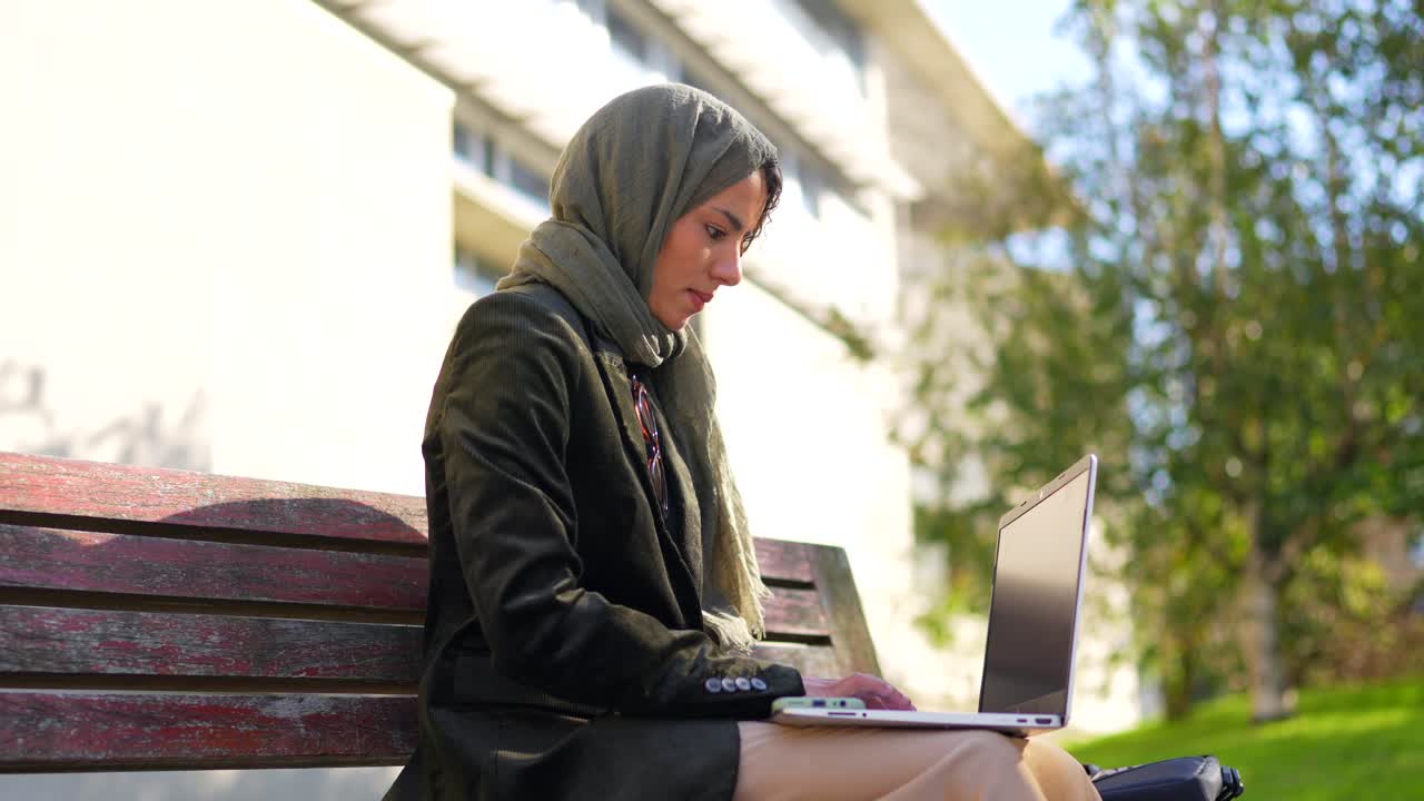 Woman in Hijab Working on Laptop Outdoors
